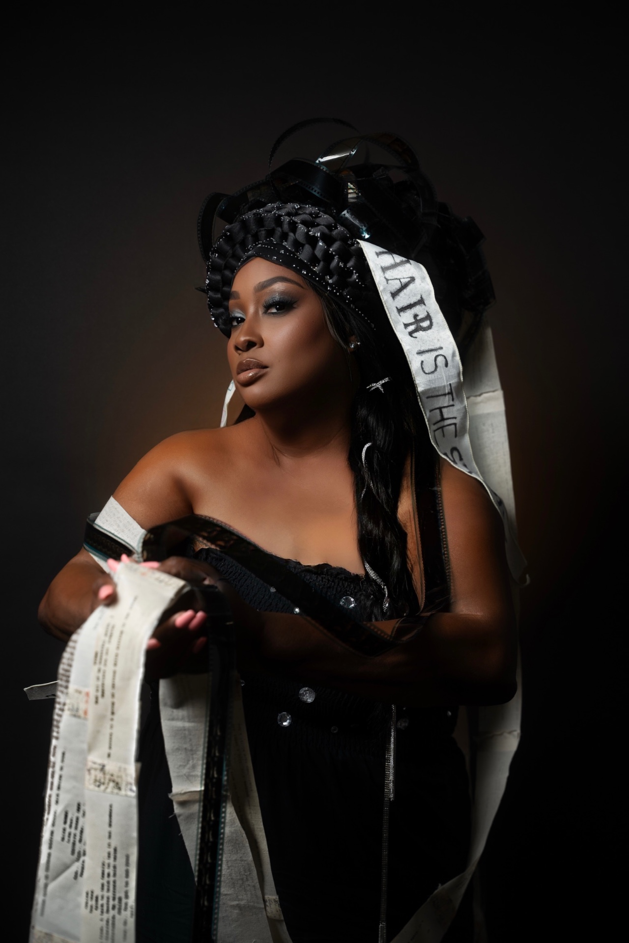 The Queen of the Story — adorned in a crown trailing ribbons of paper inscribed with 'Hair Is The Story'
